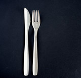 Metal knife and fork on a black background. Cooking supplies