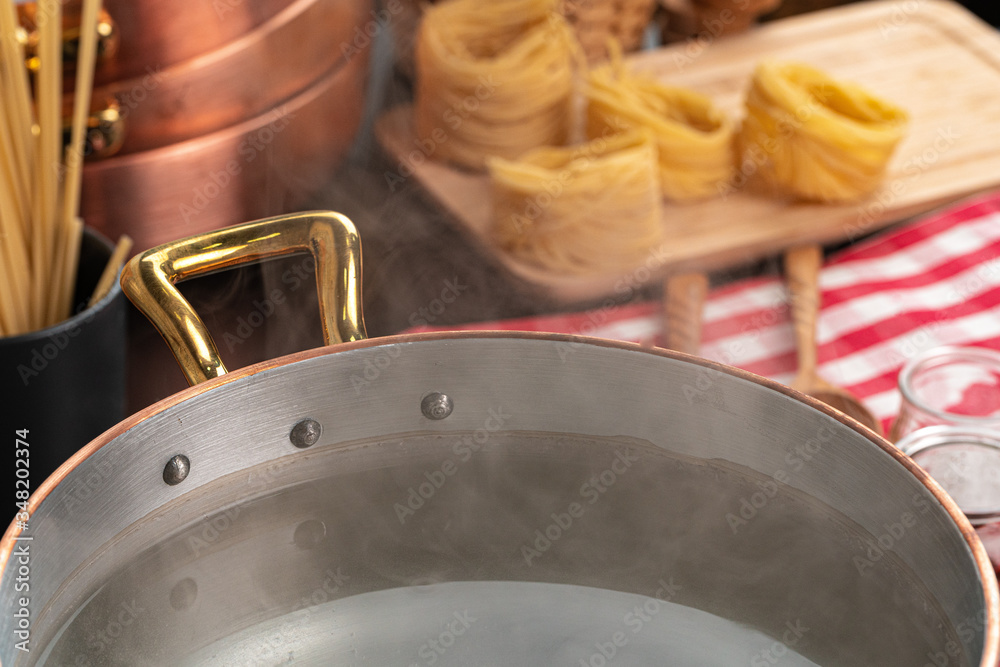 Copper pot with boiling water on a gas stove close up Copper pot with boiling water on a gas stove close up