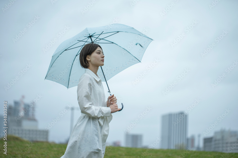 雨の中傘を挿して佇む白いワンピースを着た若い女性 Stock Photo Adobe Stock
