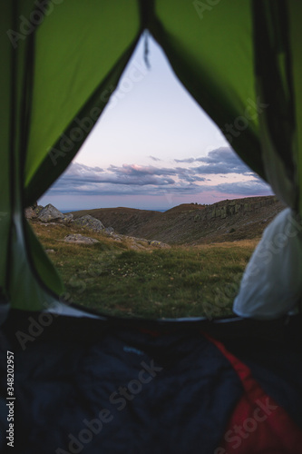 Sunset in the mountains viewed from inside a green tent.