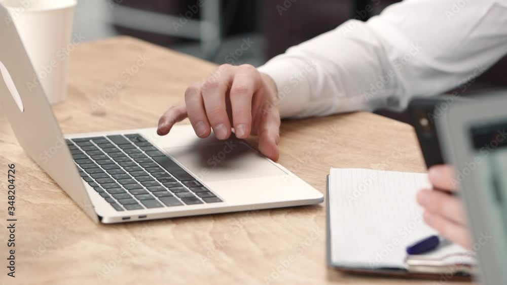 Closeup of man hands typing at laptop in the business workplace office. gesturing. concept working, desktop, device. serious concentrated male pointing. cowprking open space. two people. use phone Closeup of man hands typing at laptop in the business workplace office. gesturing. concept working, desktop, device. serious concentrated male pointing. cowprking open space. two people. use phone