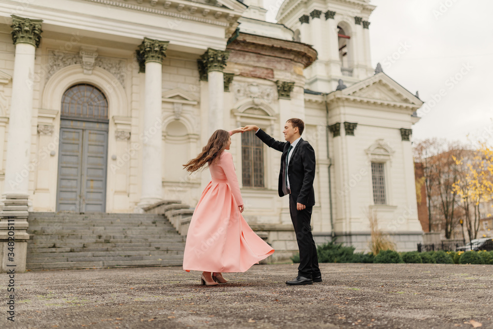 A beautiful wedding couple have fun and dancing against the background of an old architectural building. Wedding concept.