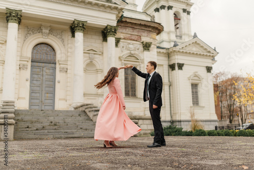 A beautiful wedding couple have fun and dancing against the background of an old architectural building. Wedding concept. © deineka
