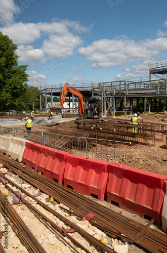 A large construction site with building equipment, safety barrier, and men with hard hats and yellow jackets