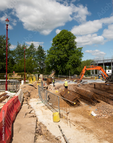 A large construction site with building equipment, safety barrier, and men with hard hats and yellow jackets