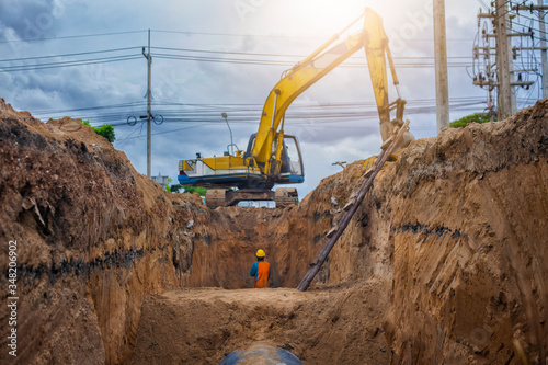 Backhoe excavator digging a trench for installation water pipeline underground at construction site.
