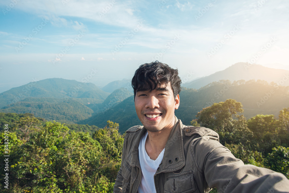Asian man traveller happy smiling take a selfie on the mountain.