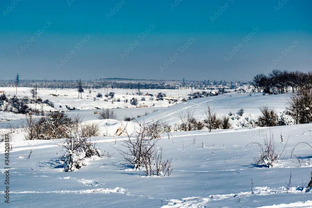 Spacious snow landscape. River and hills in Russia, white winter on the terrain, a lot of fluffy snow and ice under a beautiful blue sky. Rostov region, town of Shakhty, the river Grushevka Spacious snow landscape. River and hills in Russia, white winter on the terrain, a lot of fluffy snow and ice under a beautiful blue sky. Rostov region, town of Shakhty, the river Grushevka