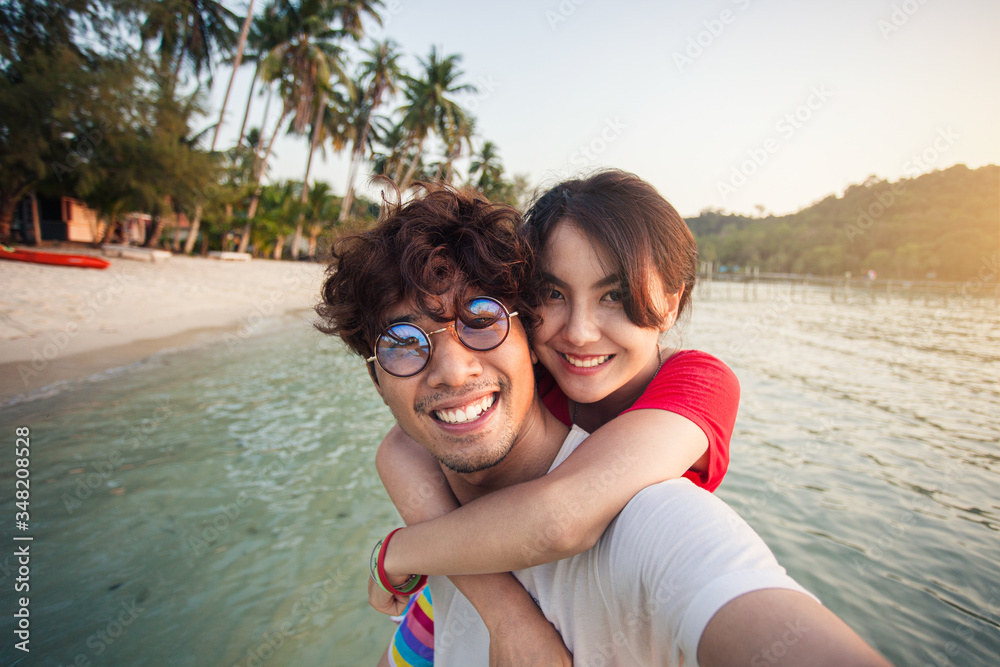 Asian young couple traveller happy in love smiling take a selfie on the beach.