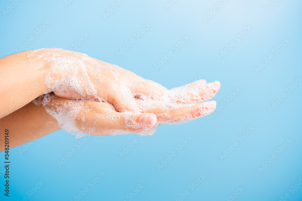 Closeup body care Asian young woman washing hands with soap have foam, hygiene prevention COVID-19 or coronavirus protection concept, isolated on blue background Closeup body care Asian young woman washing hands with soap have foam, hygiene prevention COVID-19 or coronavirus protection concept, isolated on blue background