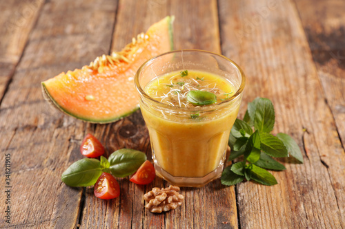 melon gazpacho with basil on wood background
