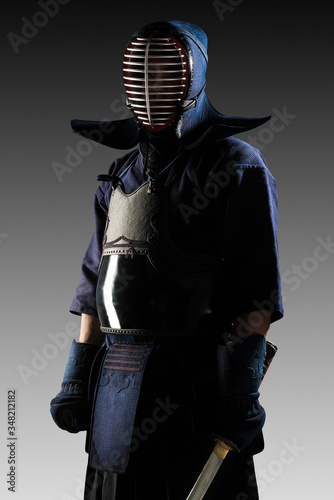 Male in tradition kendo armor with Samurai sword katana. shot in studio. Isolated on grey background photo