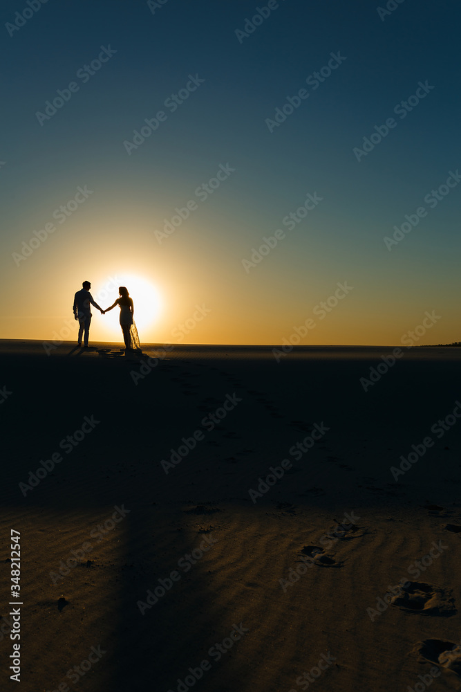 Newlyweds walk barefoot on the sand in the white desert Newlyweds walk barefoot on the sand in the white desert