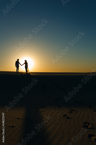Newlyweds walk barefoot on the sand in the white desert