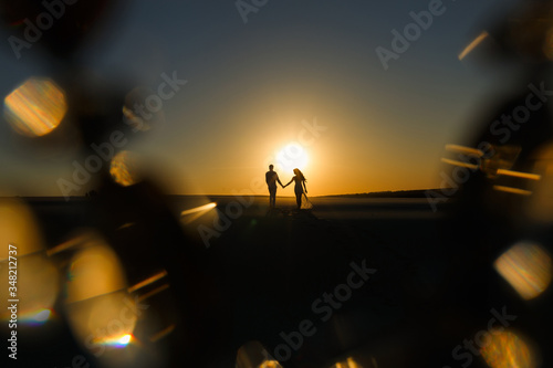 Newlyweds walk barefoot on the sand in the white desert