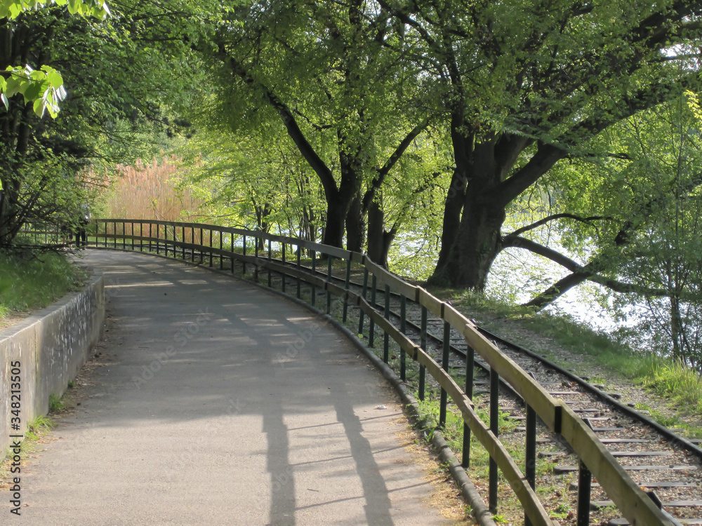 A sunlit path with a railway track alongside in Tete d'Or Park