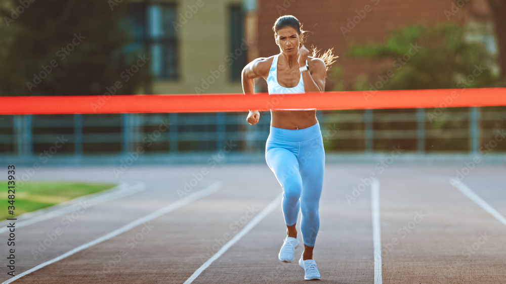Beautiful Fit Female Runner Crossing the Finish Line on a Professional Sports Arena. Athletic Woman Competing at a Stadium. Celebrating Victory Achievement. Beautiful Fit Female Runner Crossing the Finish Line on a Professional Sports Arena. Athletic Woman Competing at a Stadium. Celebrating Victory Achievement.