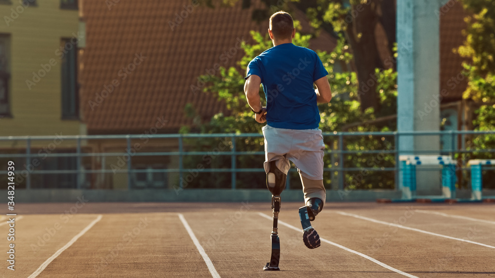 Athletic Disabled Fit Man with Prosthetic Running Blades is Training on a Outdoors Stadium on a Sunny Afternoon. Amputee Runner Jogging on a Stadium Track. Motivational Sports Shot.
