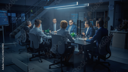 In the Modern Corporate Meeting Room: Diverse Group of Businesspeople, Lawyers, Executives and Directors Talking, Negotiating, Working with Documents, Planning Strategy. Late at Night in the Office