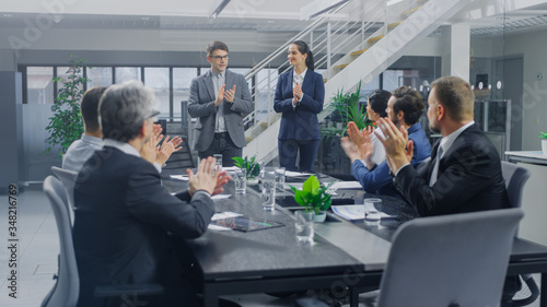 In the Corporate Office Meeting Room: Two Young and Ambitions Start-up Creators Give a Speech to a Group of Venture Capital Investors, Businesspeople Cheer and Applaud in Successful Agreement