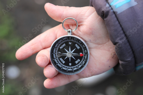 Old classic navigation compass in childs hand on natural background