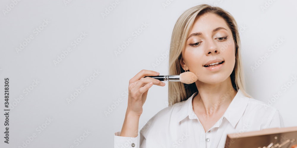A pretty young woman is using different make-up accessories for application of make-up