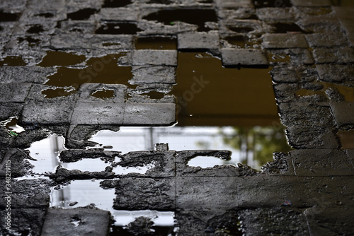 Obraz na plátne broken street road of paving stones with puddles of sewage in poor area