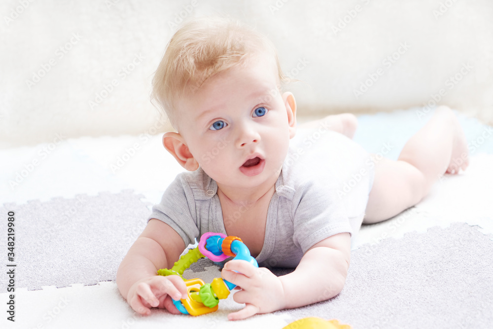 The baby s teeth are being cut. A cute kid with blue eyes is playing with toy The baby s teeth are being cut. A cute kid with blue eyes is playing with toy