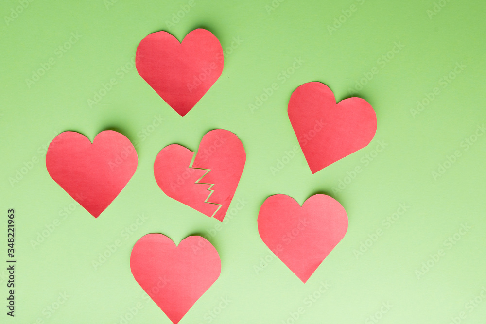 Five paper hearts surrounding one '' broken, lonely, down '' Green background.