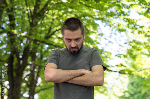 A bearded young man walks out of the park in anger. Emotional expression of anger