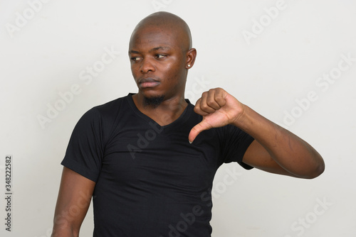 Stressed young bald African man giving thumbs down