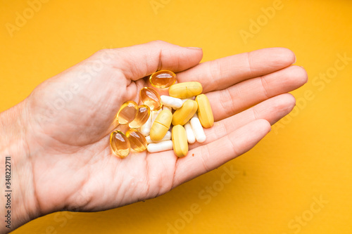 human hand with pills on yellow background