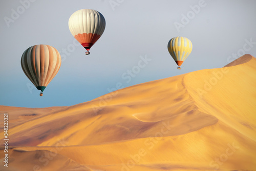 Colored hot air balloons flying over the sand dunes at sunset. Africa, Namibia © Yuliia Lakeienko