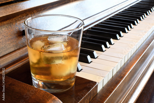 Glass of whisky close to a piano keyboard photo