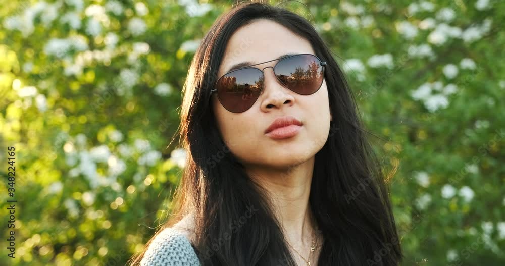 Cool fashionable asian girl posing with sunglasses. Walking in park at sunset. Cool fashionable asian girl posing with sunglasses. Walking in park at sunset.