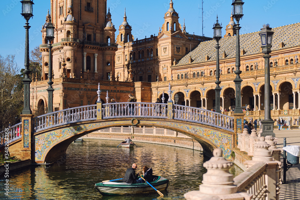Fototapeta premium Tourists go on row boat around the water of Guadalquivir river in Plaza de Espana. Seville, Spain