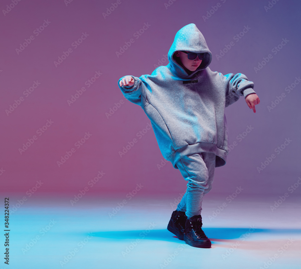 Cool boy child dancing hip hop in a hoodie and glasses, in a Studio on a  neon background. Stock Photo | Adobe Stock