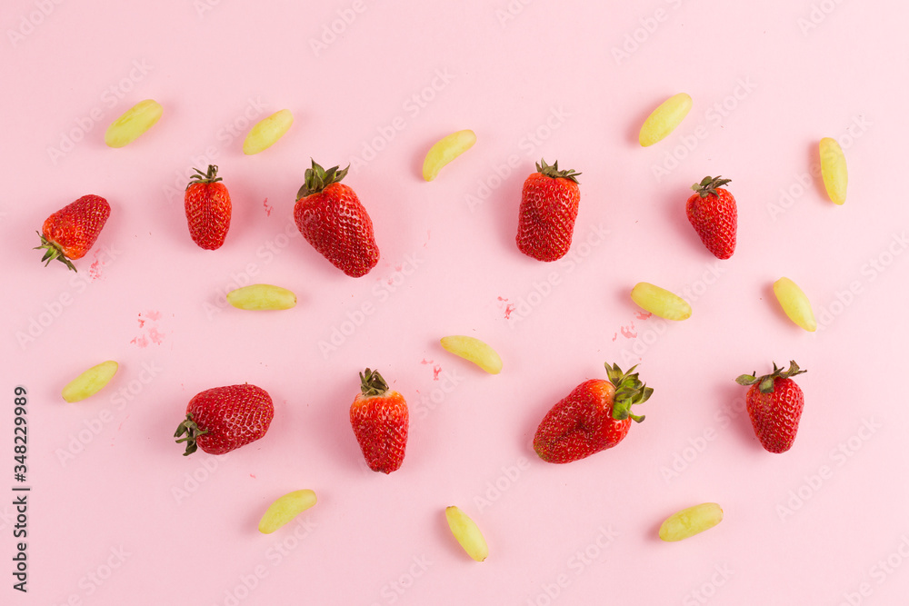 strawberries and grapes on a pink background strawberries and grapes on a pink background