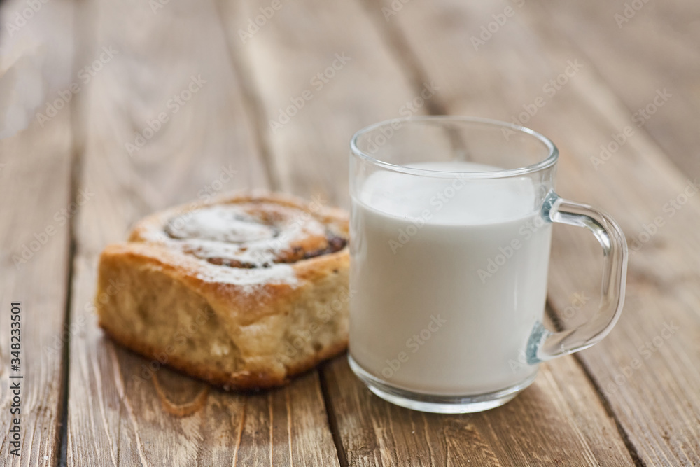 Basket of homemade buns with jam, served on old wooden table with cup of milk Basket of homemade buns with jam, served on old wooden table with cup of milk