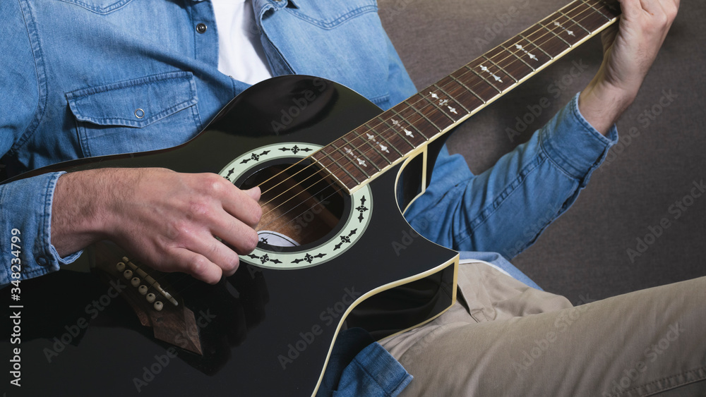 Fototapeta premium Man playing an black acoustic guitar