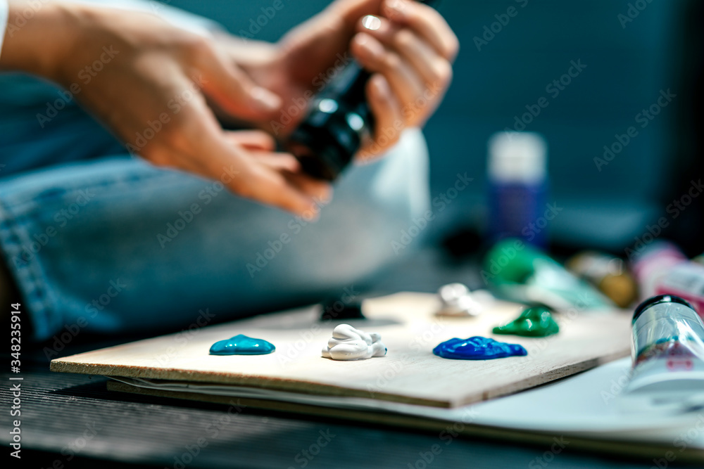 Time for Art. Painter putting acrylic paints on wooden palette before working process. Female artist adds colors to the palette. Horizontal shot. Selective focus Time for Art. Painter putting acrylic paints on wooden palette before working process. Female artist adds colors to the palette. Horizontal shot. Selective focus