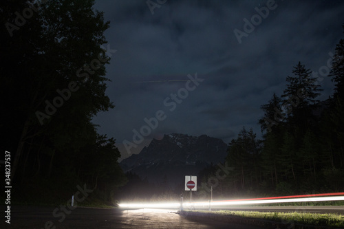 Night highway close up shot from low angle in mountins. luminous road with grey wet  asphalt. Traveling around the world. Drive a car in the night. Darkness on roadway. Unusual foreshortening. Nodoby.