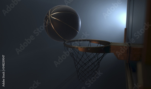 An action shot of a black and gold basketball teetering on the rim of a regular basketball hoop dramatically spotlit from behind on an isolated dark background - 3D render © alswart