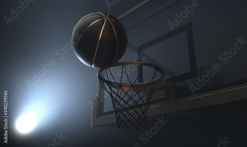 An action shot of a black and gold basketball teetering on the rim of a regular basketball hoop dramatically spotlit from behind on an isolated dark background - 3D render © alswart