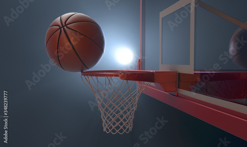 An action shot of a regular basketball teetering on the rim of a red basketball hoop dramatically spotlit from behind on an isolated dark background - 3D render © alswart