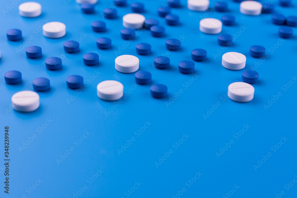Medical background of white and blue pills on a blue background.Many sedative drugs.Copy space. Medical background of white and blue pills on a blue background.Many sedative drugs.Copy space.