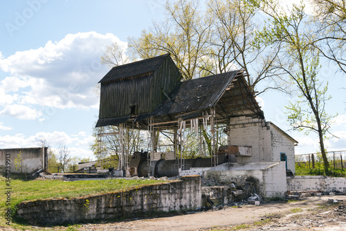 Old abandoned wood mill in spring time. Sunny day. Old mill on the background of the landscape. Historical destroyed building in belarusian village. Countryside with ancient traditional mill.