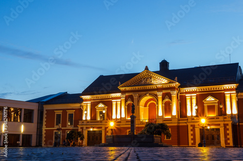 Buildings in night city with lantern. Lithuanian town. Center of Klaipeda. Night life. Empty street with lighted buildings. Walking through the street. Deep blue sky and historical house.  Twilight.