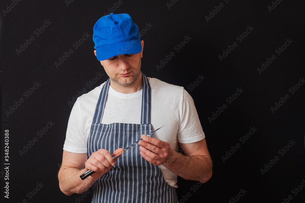 Φωτογραφία Portrait of a professional butcher in black and white apron, white t shirt and blue baseball hat