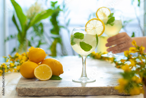 Citrus iced lemonade in pitcher and lemons glasses with lemon slice decoration and on marble table hand with cocktail